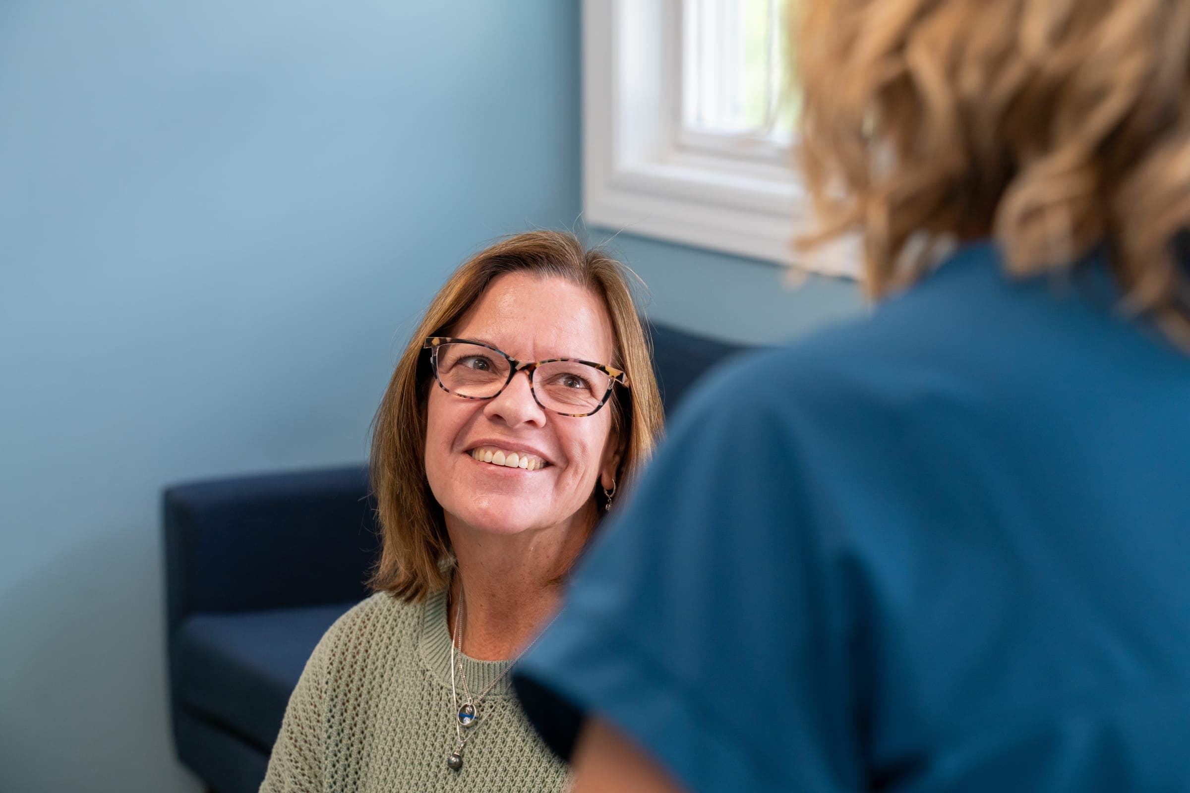 A patient smiling while talking with a Doctor of Audiology at Sounds of Life