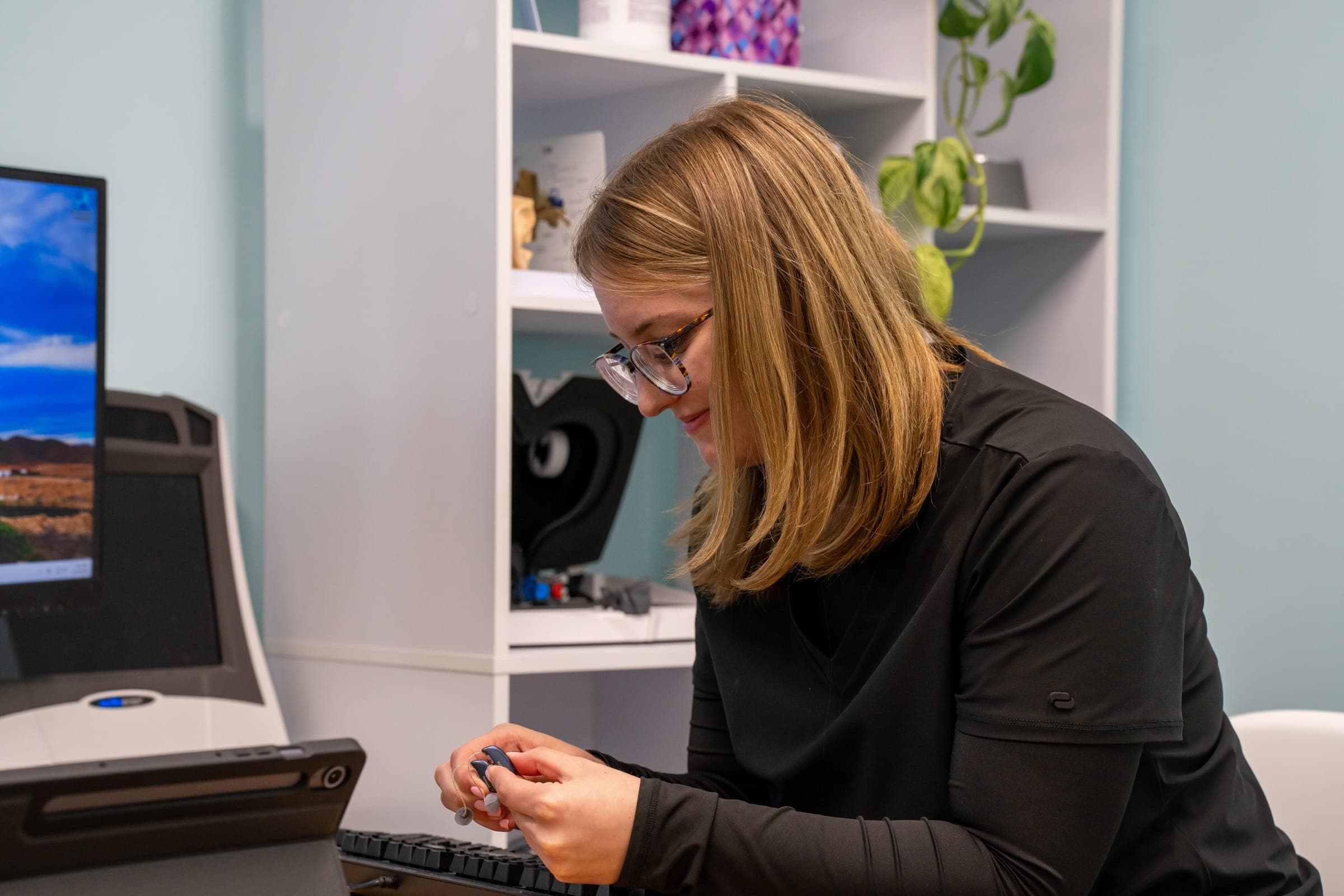 Audiologist checking a hearing aid at the desk