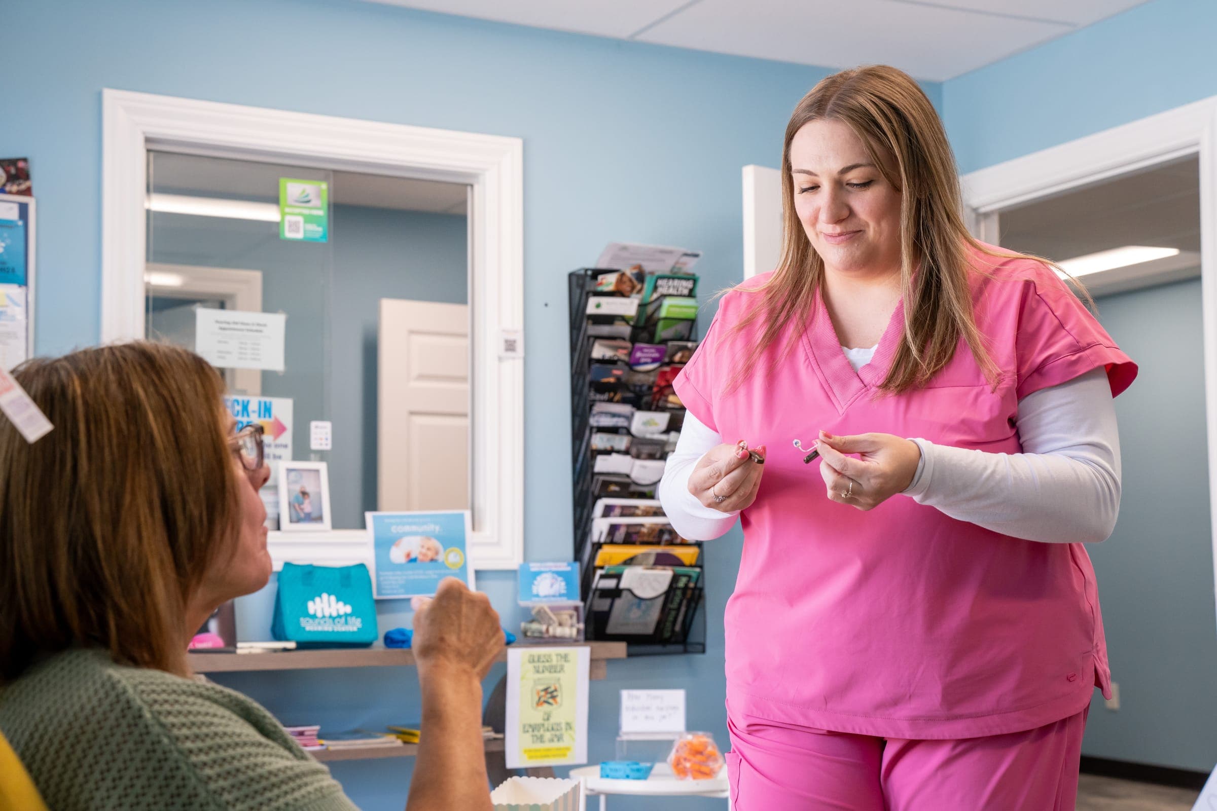 Staff member fitting a hearing aid with a patient