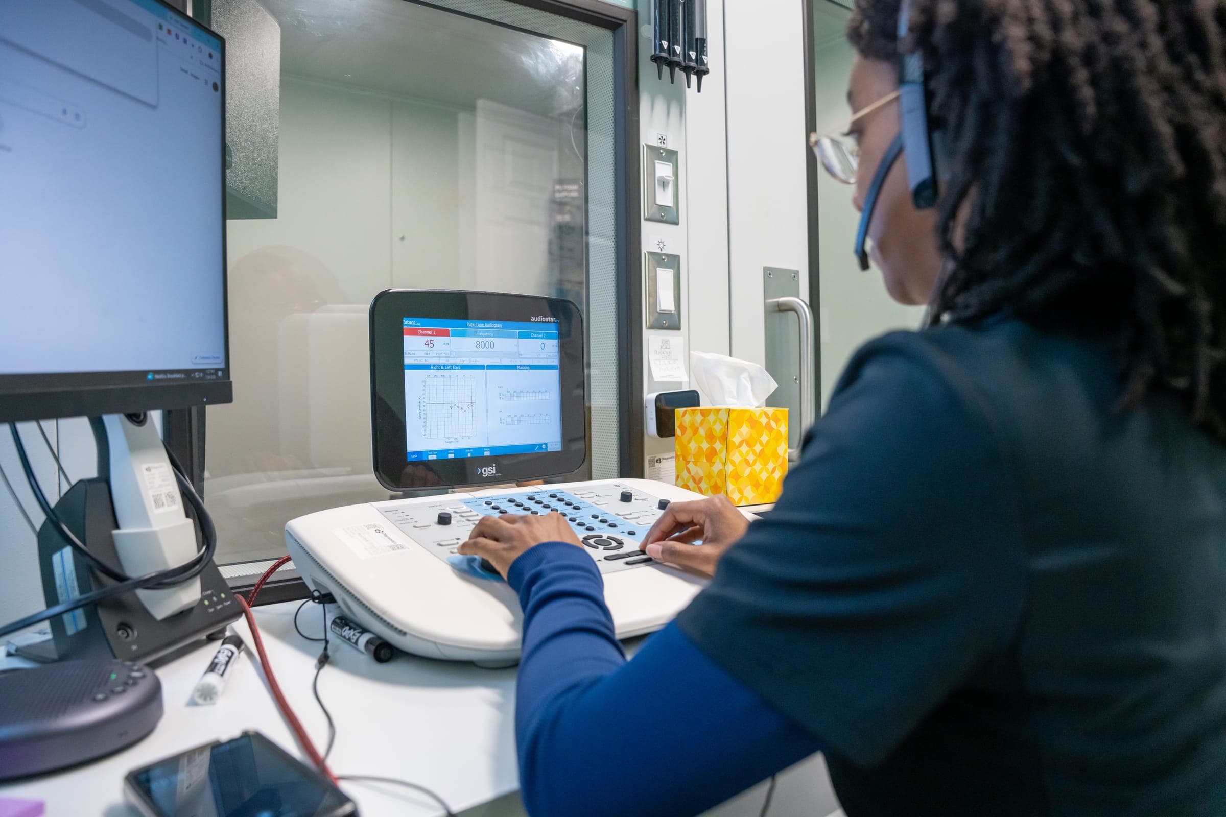 Audiologist wearing a headset at the audiometer
