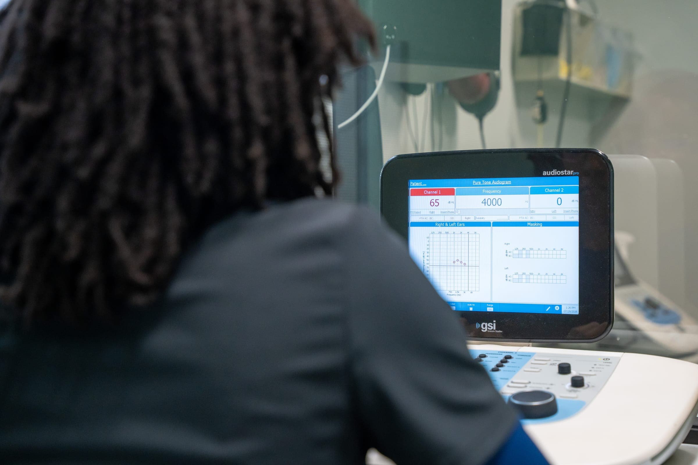 Audiologist at the audiometer reviewing test results on screen