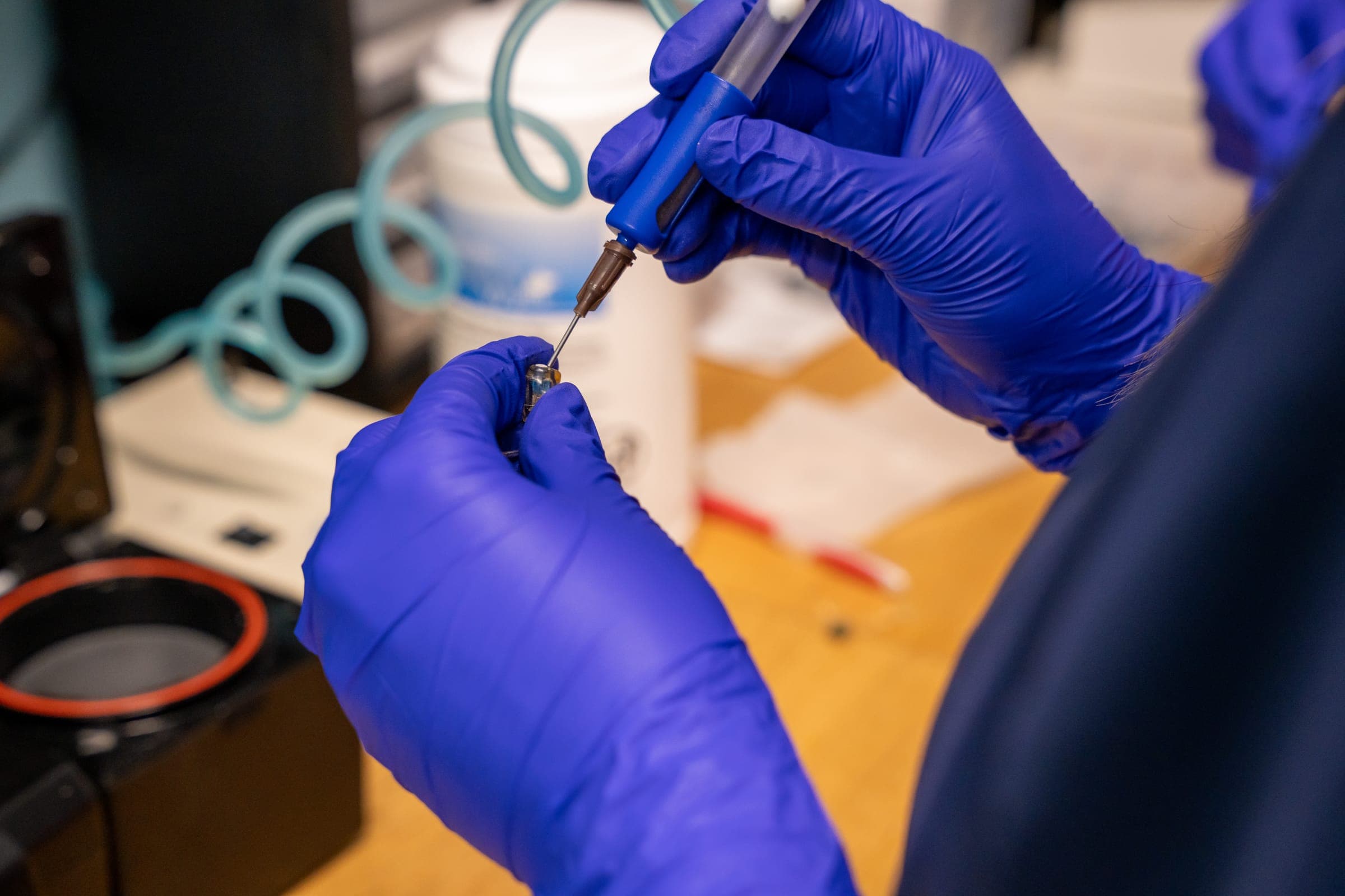 Technician cleaning a hearing aid receiver in the lab