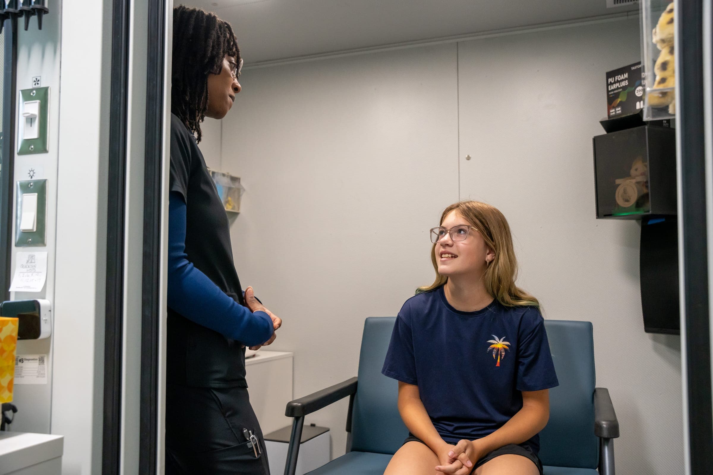 Audiologist talking with a young patient in the sound booth